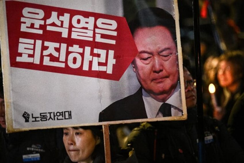 A woman holds a sign that reads "Yoon Suk Yeol should step down" during a candlelight vigi