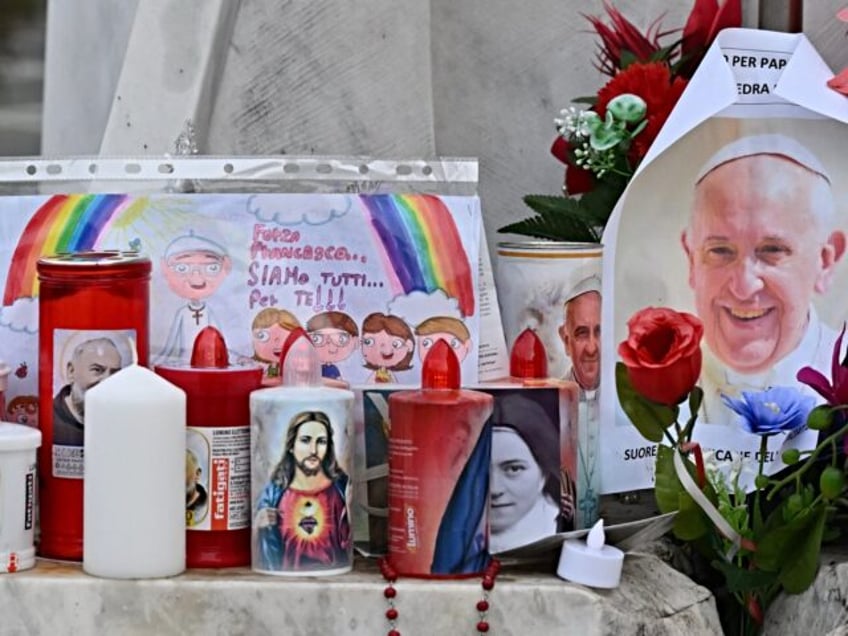 Candles, flowers and a portrait of Pope Francis are laid at the statue of John Paul II out