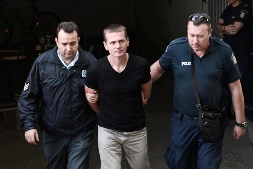 Russian Alexander Vinnik (C) is escorted by police officers as he arrives at a courthouse