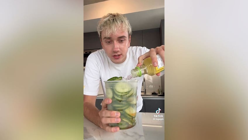 Man pouring rice vinegar into a container of cucumbers.