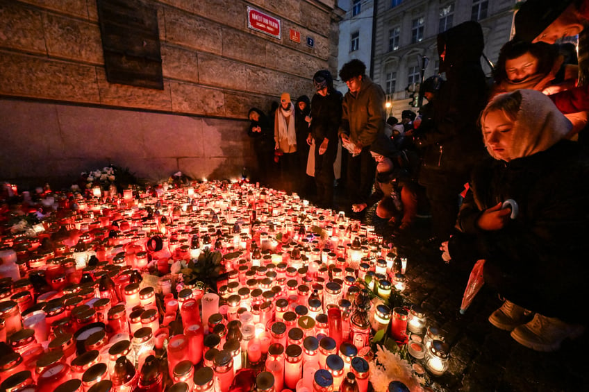 People place candles and flowers at a makeshift memorial for the the victims of the Charles University's shooting, outside the Charles University in central Prague, on December 23, 2023, during a national mourning day. Flags on public buildings flew at half mast December 23, 2023 and masses were scheduled across the Czech Republic for a day of national mourning after a deadly shooting at Prague's Charles University -- the worst in the country in decades. A 24-year-old student opened fire at the Faculty of Arts on December 21, 2023, killing 13 people and then himself. Another person died in hospital later on. (Photo by Michal Cizek / AFP) (Photo by MICHAL CIZEK/AFP via Getty Images)