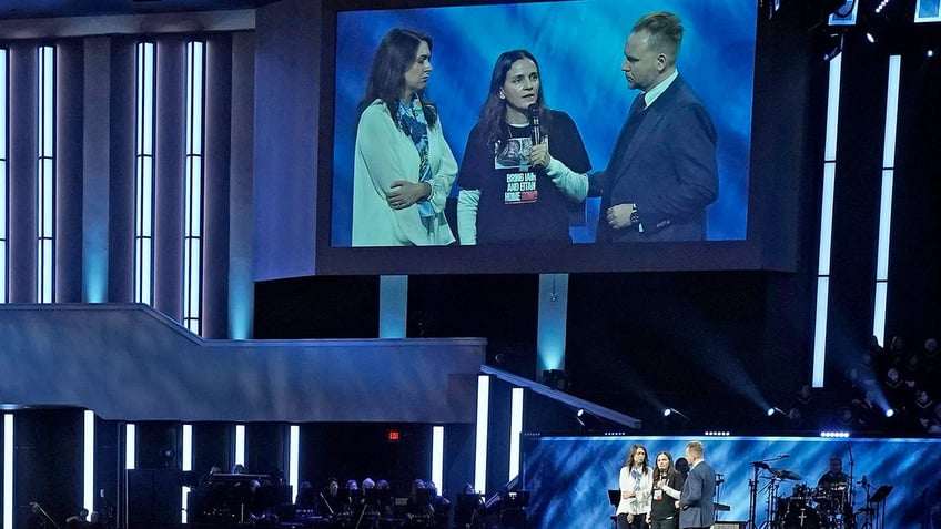 two women and a man in a suit on a screen