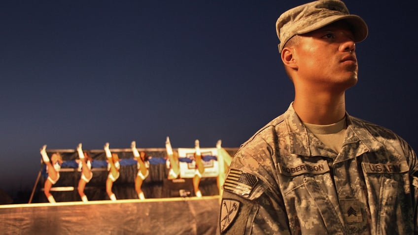 A servicemen standing in front of the Dallas Cowboys cheerleaders