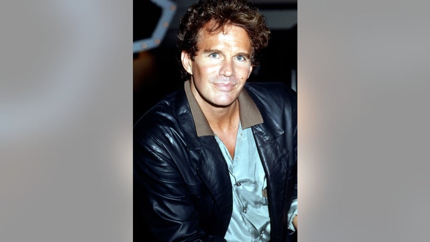 Dack Rambo wearing a black leather jacket and a light blue shirt.