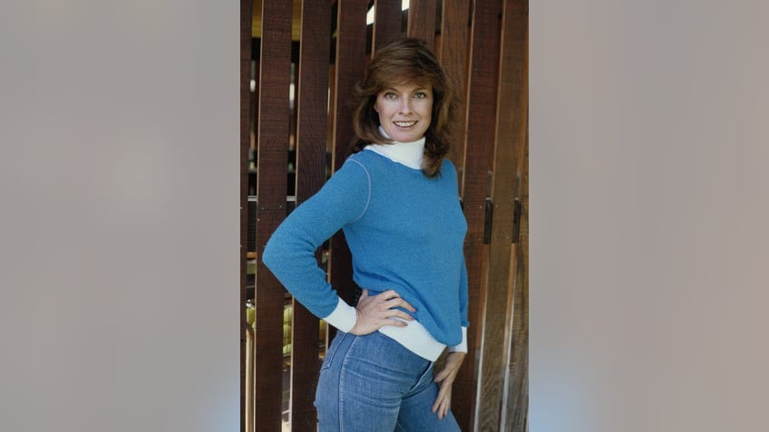 Linda Gray posing near a fence in the 1980s