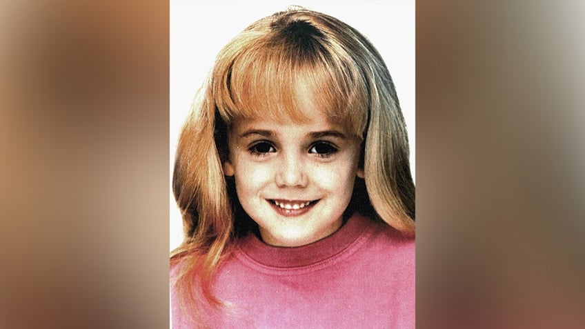 JonBenét Ramsey wearing a pink sweater smiling.