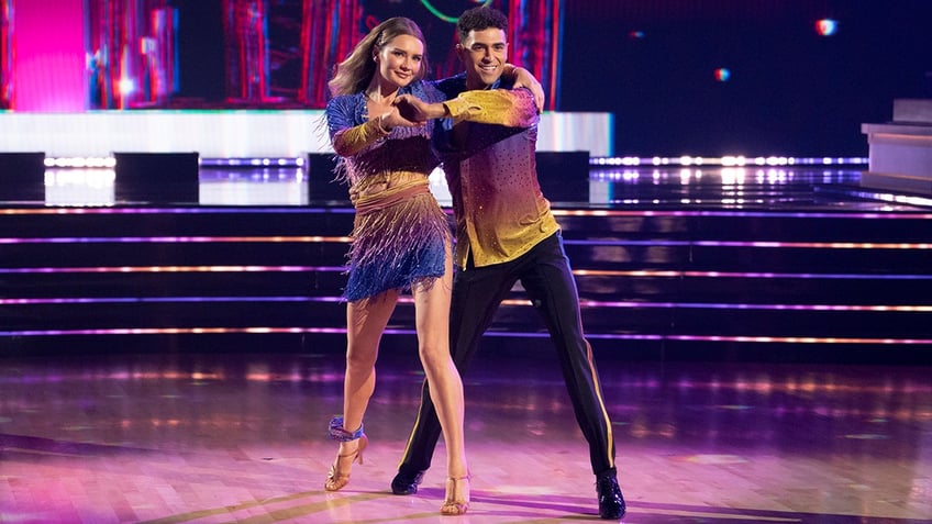 Anna 'Delvey' Sorokin and Ezra Sosa in a matching purple and yellow attire dance on "Dancing with the Stars"