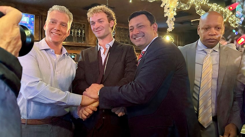 Daniel Penny, center, poses for a photo while gathered at a bar with his attorneys, Steven Raiser, left, and Thomas Kenniff after being acquitted of criminally negligent homicide