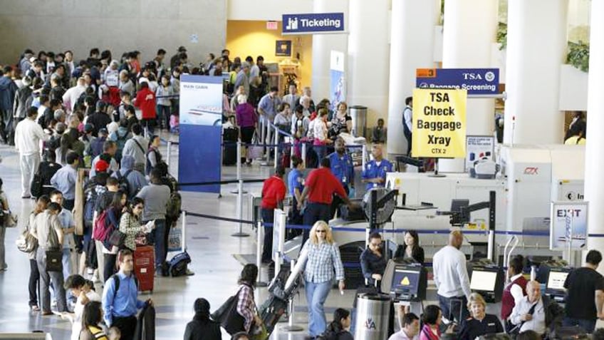 Crowded airport shows travelers waiting in lines.