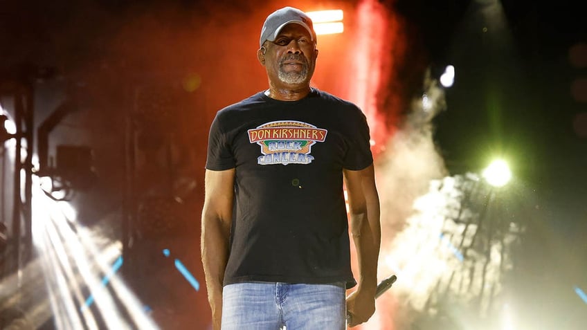 darius rucker standing on stage holding a mic at his side 