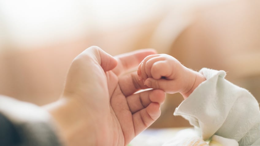 Mother and baby holding hands