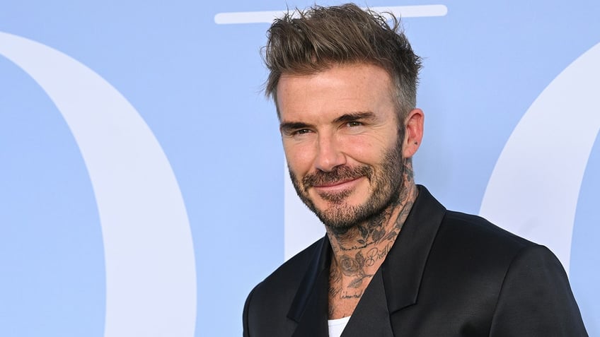 David Beckham smiles while wearing black blazer.