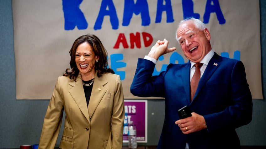 GLENDALE, ARIZONA - AUGUST 9: Democratic presidential candidate, U.S. Vice President Kamala Harris and Democratic vice presidential candidate Minnesota Gov. Tim Walz laugh after taking a selfie in front of a sign that reads "Kamala and The Coach" during stop at a campaign office on August 9, 2024 in Glendale, Arizona. Kamala Harris and her newly selected running mate Tim Walz are campaigning across the country this week. (Photo by Andrew Harnik/Getty Images)