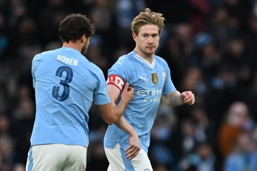 Over to you: Manchester City's Ruben Dias (L) passes the captain's armband to Kevin De Bruyne