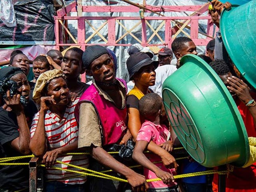 People wait for a food distribution in a displaced persons camp at the Lycée Marie Jeanne