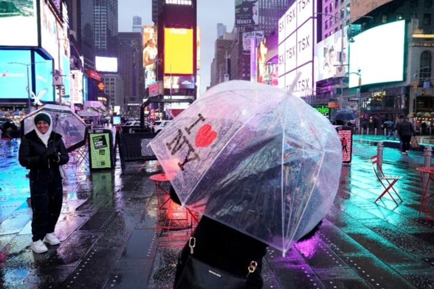 People carry umbrellas on Times Square in New York as the northeastern US is hit by bad weather