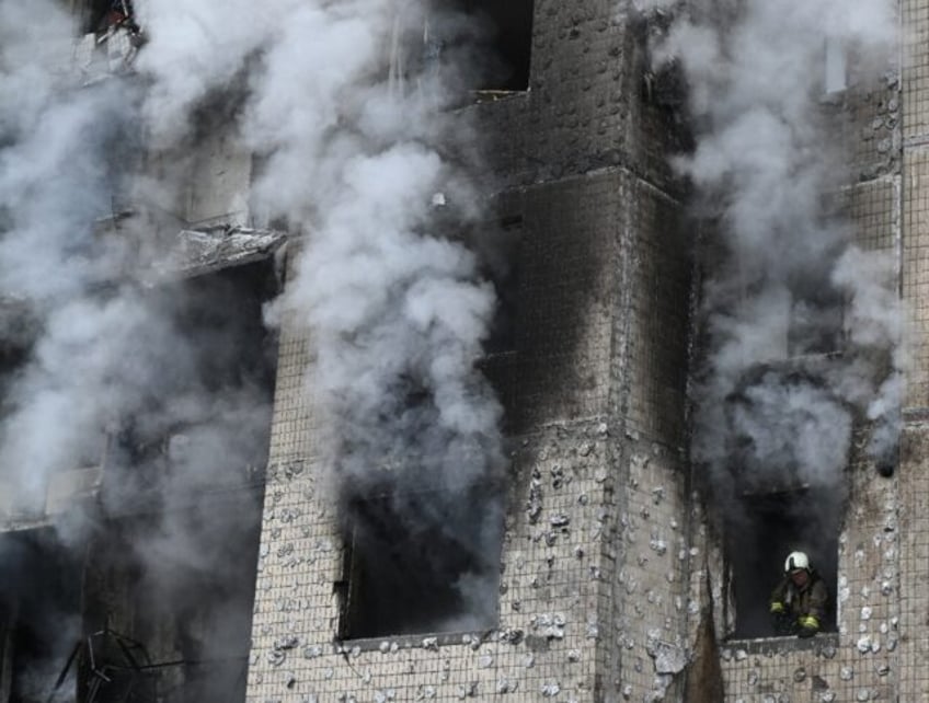 A firefighter looks out of a window after a strike in Kyiv