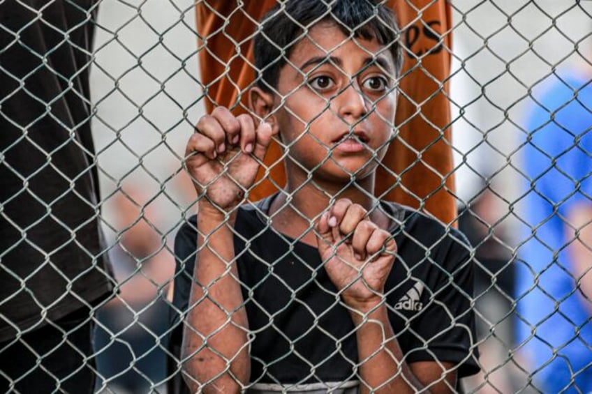 A boy watches on as the bodies of victims killed in Israeli bombardment arrive at the Nass