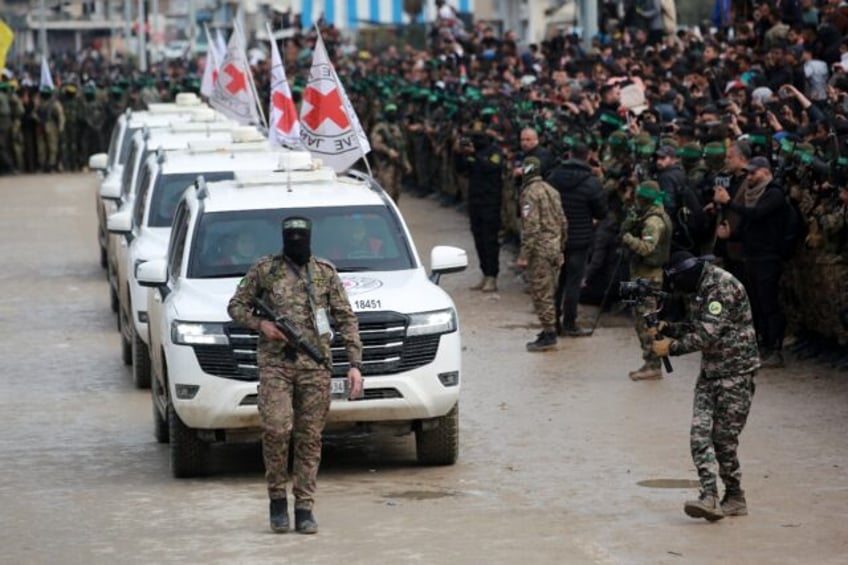 A Palestinian Hamas fighter precedes International Red Cross vehicles as they arrive in th