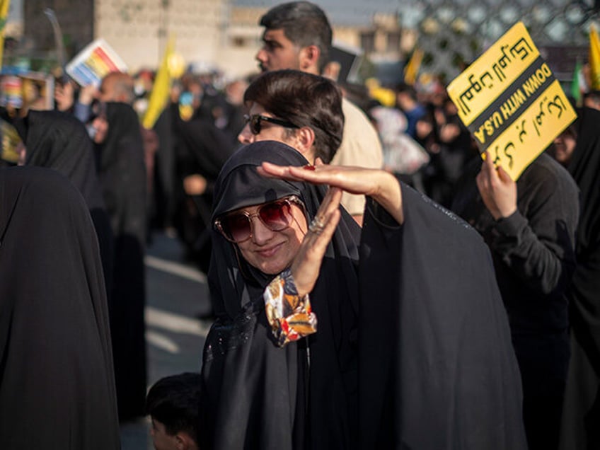 A veiled Iranian woman demonstrates a T-hand gesture used by Lebanon's Hezbollah Secretary