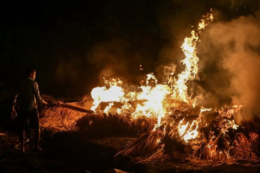 A man torches funeral pyres of victims who died after consuming toxic alcohol during a mas