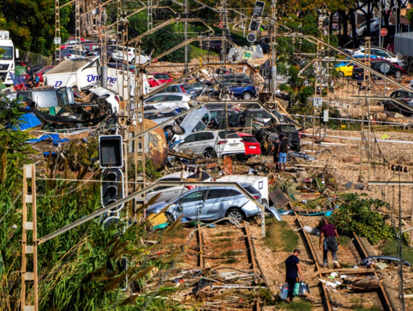 People walk among flooded cars piled up in Valencia, Spain, Thursday, Oct. 31, 2024. (AP P