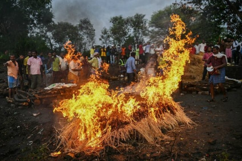 Family members perform last rites during the funeral of victims who died after consuming t