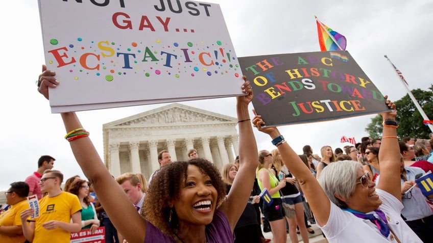 Ikeita Cantu, left, and her wife Carmen Guzman, of McLean, Va., hold up signs as they celebrate outside of the Supreme Court in Washington, Friday June 26, 2015, after the court declared that same-sex couples have a right to marry anywhere in the US. The couple was married in Canada in 2009 when gay marriage was illegal in Virginia. (AP Photo/Jacquelyn Martin)