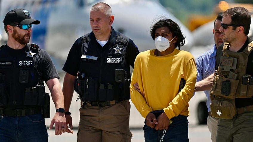 Murder suspect in handcuffs is escorted by law enforcement