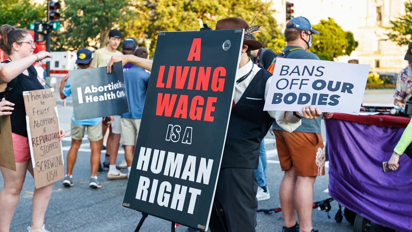 A protester holds a sign reading, "A Living Wage is a Human Right."