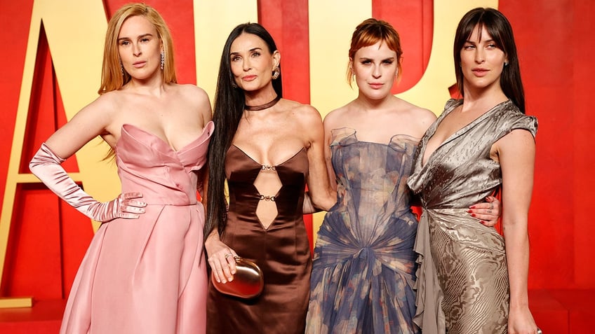 Rumer Willis in a strapless pink dress attends the Vanity Fair Oscars party and poses with mother Demi Moore in a brown cutout dress and sisters Tallulah and Scout