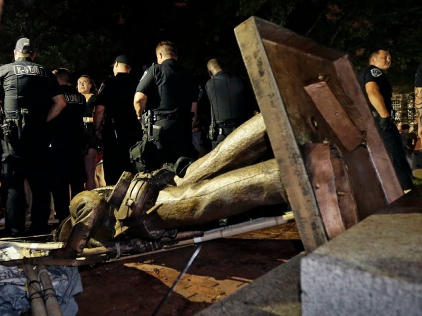 Police stand guard after the confederate statue known as Silent Sam was toppled by protesters on campus at the University of North Carolina in Chapel Hill, N.C., Monday, Aug. 20, 2018. (AP Photo/Gerry Broome)