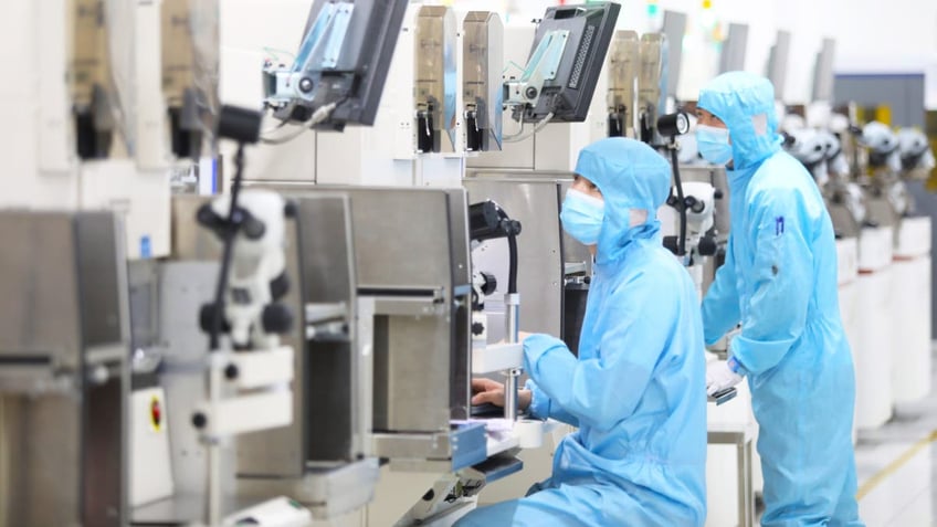 Workers are checking the production of electronic chips at a production workshop of the company's radio frequency and power device manufacturing center in Chongqing, China, on May 9, 2023.