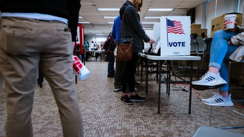 Election officials and voters stand near an electronic ballot booth in Fairdale High School November 3, 2020 in Louisville, Kentucky. (Photo by Jon Cherry/Getty Images)