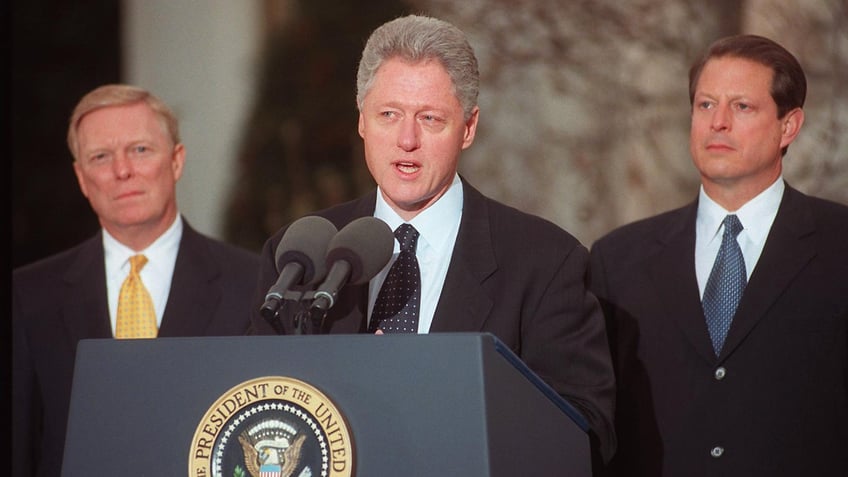 Bill Clinton speaking at lectern with Dick Gephardt and Al Gore behind him