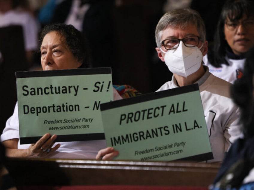 People in the audience hold up signs in support of immigrants as the Los Angeles City Coun