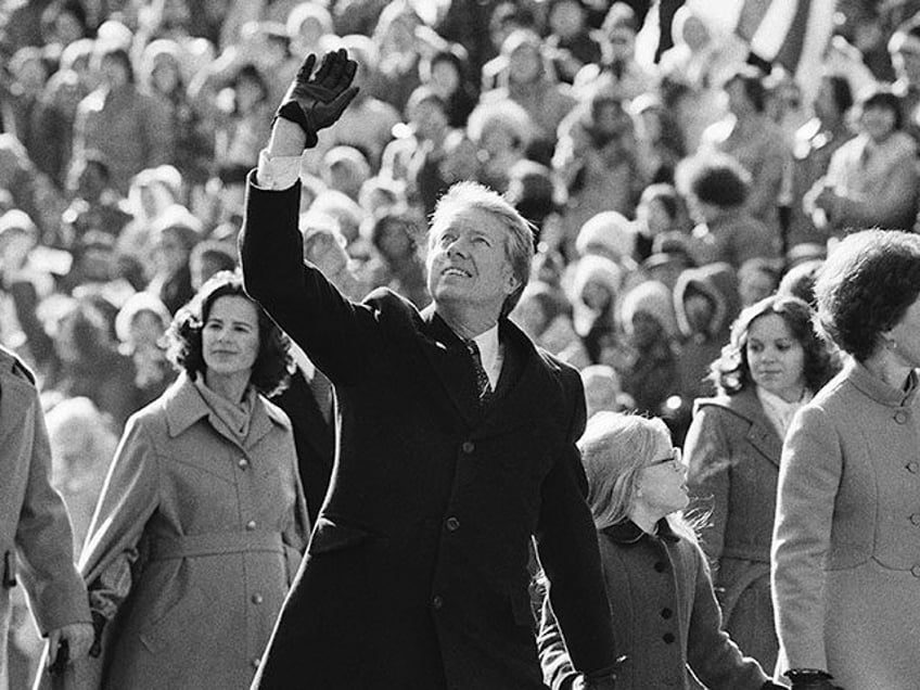 President Jimmy Carter waves to the crowd while walking with his wife Rosalynn and their d