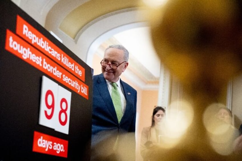 Senate Majority Leader Chuck Schumer stands next to a poster that reads "Republicans kille