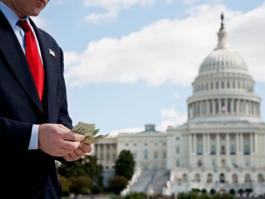 A politician counting money in front of the US Capitol Building - stock photo