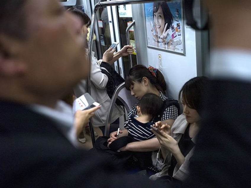 In this picture taken on May 8, 2015, a mother holds her child in the subway in Tokyo. AFP PHOTO / FRED DUFOUR (Photo credit should read FRED DUFOUR/AFP via Getty Images)