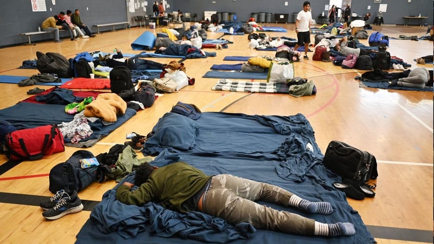 A migrant lies on the sleeping pad at a makeshift shelter in Denver, Colorado