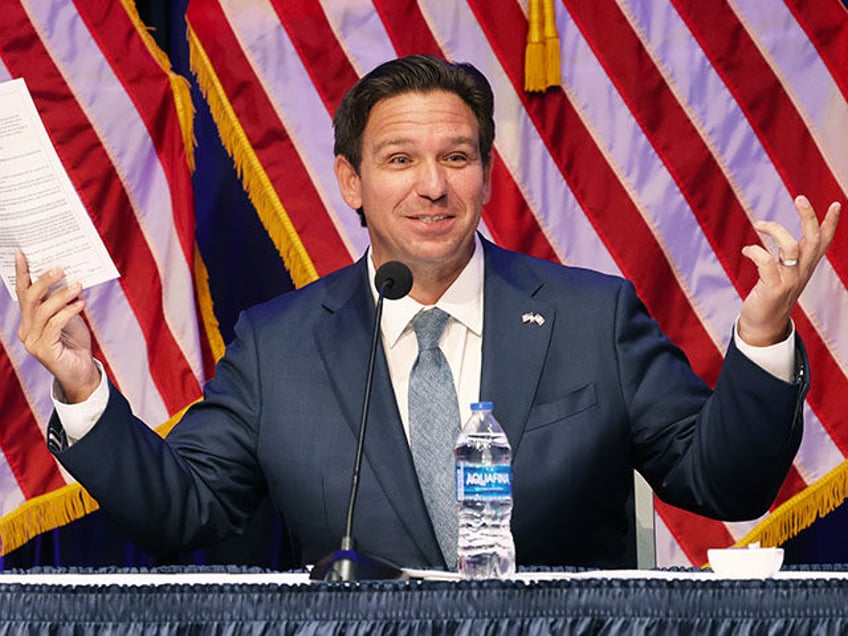 Florida Governor Ron DeSantis, center, speaks as he holds a copy of the amendment at his p