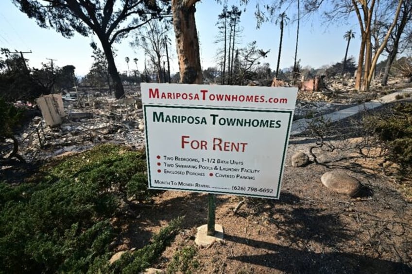 The remains of townhomes destroyed by the Eaton Fire lie behind an advertising sign in Alt