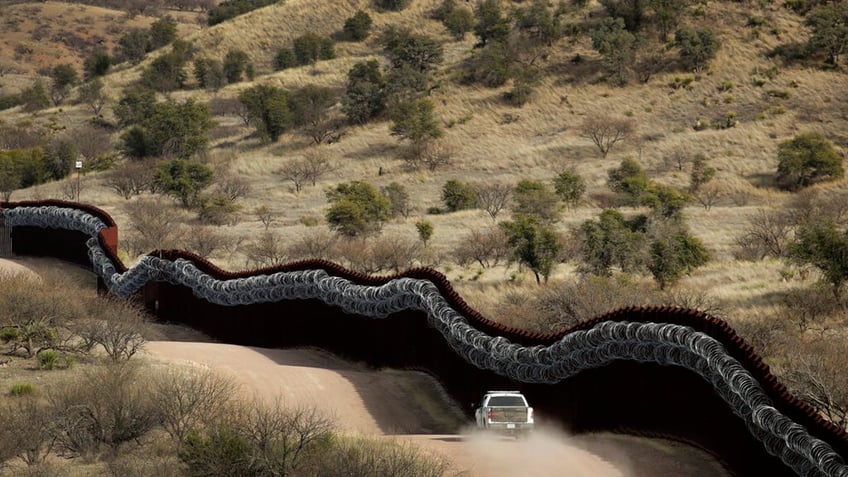 truck going down road along border in desert area