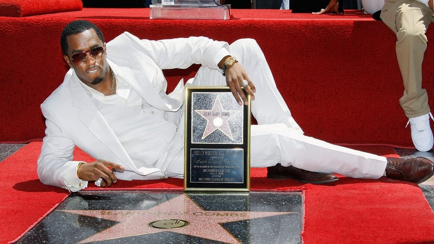 Diddy in an all-white suit poses at his star on the Hollywood Walk of Fame