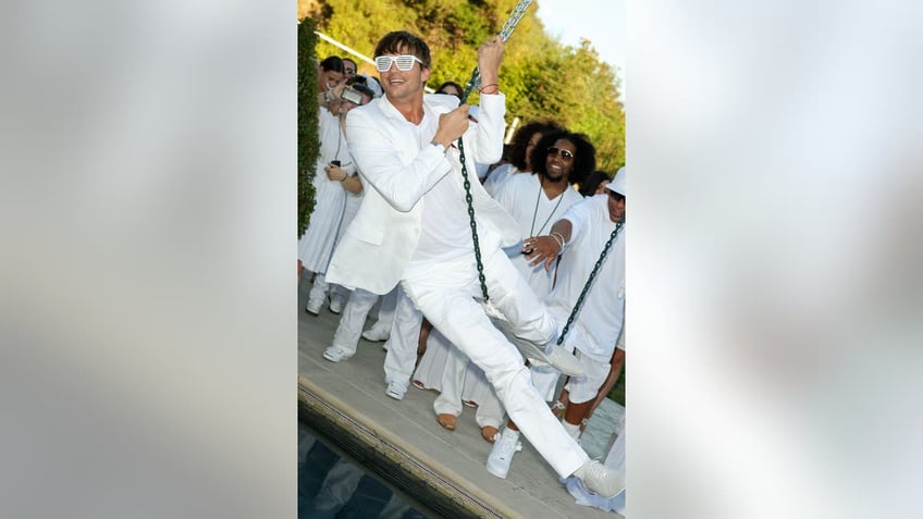 Ashton Kutcher swinging on a swing at the White Party