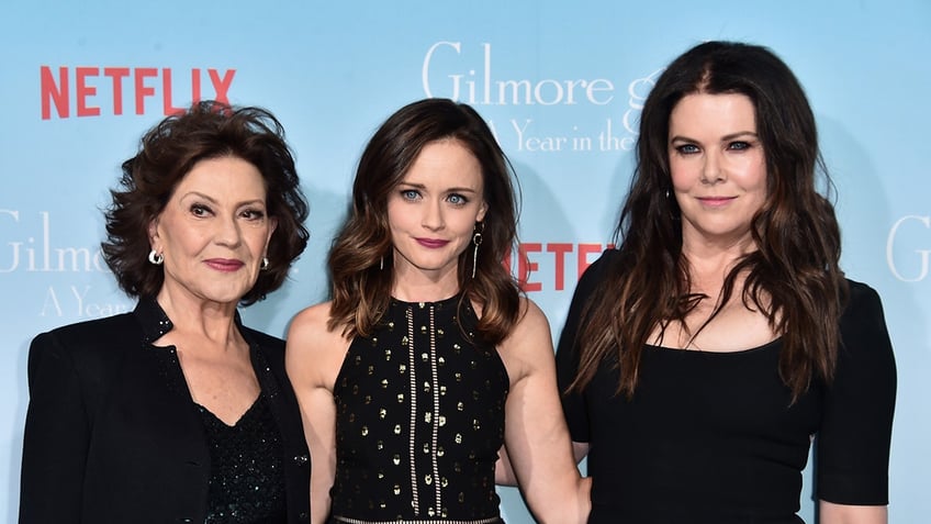 The cast of Gilmore Girls standing together wearing black