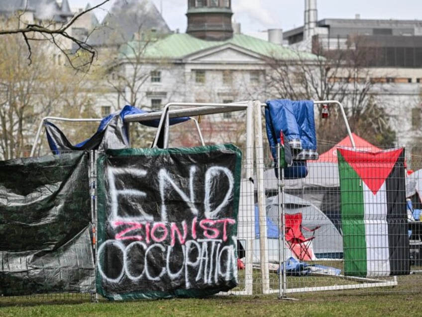 Banners and a Palestinian flag hang on a fence at a pro-Palestinian protest encampment on