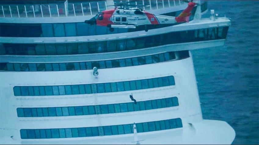 US coast guard personnel gets lowered onto cruise deck from helicopter