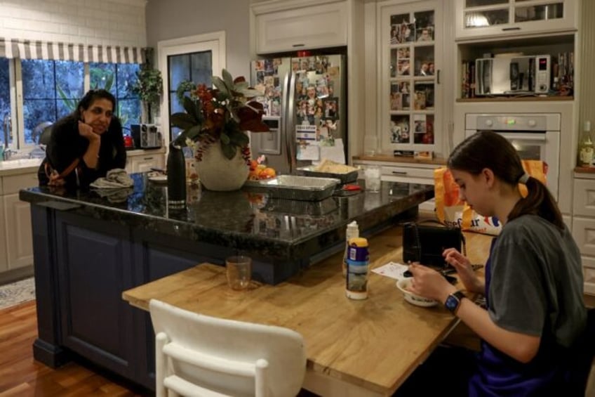 Sigal Chayak, displaced from northern Israel, looks on as her daughter Shani tastes the fo